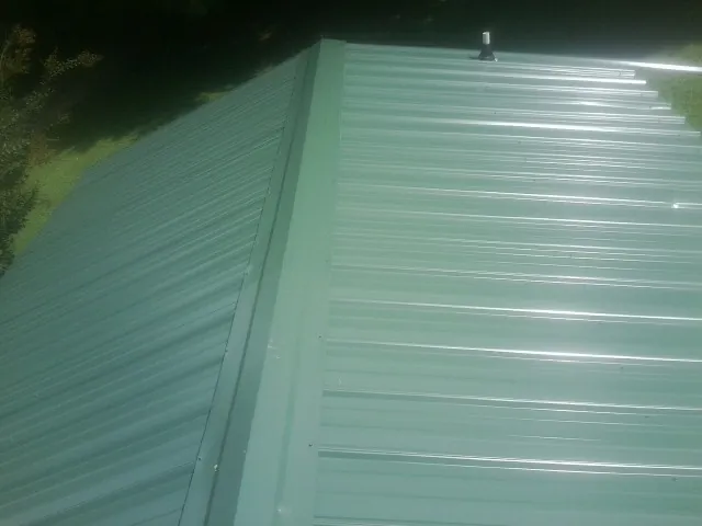 New green metal panels meeting at the ridge of a roof — Flat Roof Repair work by our crew in Port Wentworth